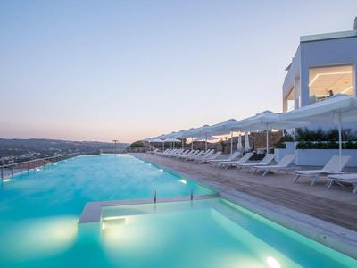 Infinity bazén s lehátky a moderní architekturou za západu slunce.