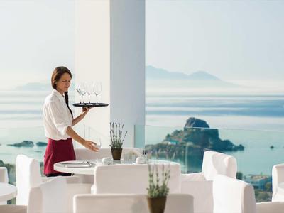 Kelnerka z tacą w nowoczesnym ogródku z widokiem na morze.