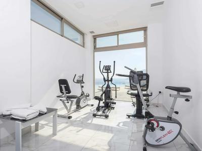 Světelná posilovna se třemi cvičebními stroji a velkými okny.