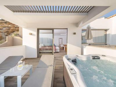 Taras z jacuzzi, leżakami i nowoczesnym zestawem wypoczynkowym przy pokoju hotelowym.