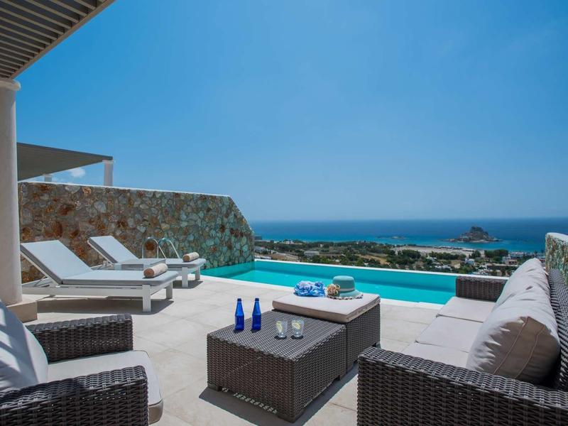 Nowoczesna przestrzeń na zewnątrz z basenem, meblami wypoczynkowymi i widokiem na morze przy czystym niebie.