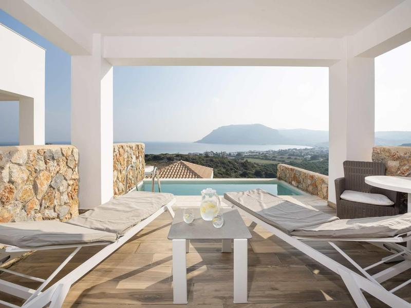 Taras z basenem, leżakami i widokiem na góry oraz morze przy czystym niebie