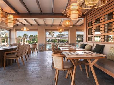 Moderní, útulná restaurace s dřevěným nábytkem a výhledem ven.