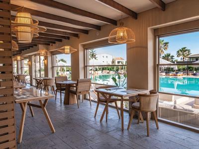 Moderner Hotelrestaurantbereich mit Holztischen und Blick auf den Pool.