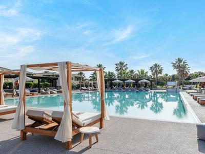 Großer Pool mit Sonnenliegen und Pavillons bei sonnigem Wetter in einem Hotelresort.