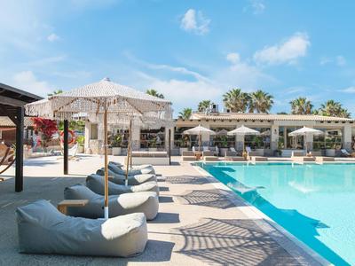 Moderní bazénová část s slunečníky a pohodlnými sedacími vaky pod modrou oblohou.