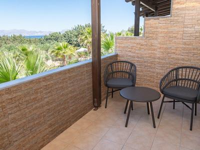 Pohodlný balkon se dvěma černými židlemi a malým kulatým stolem s výhledem na zeleň.