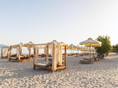 Strand mit luxuriösen Himmelbetten und Sonnenschirmen bei Sonnenaufgang.