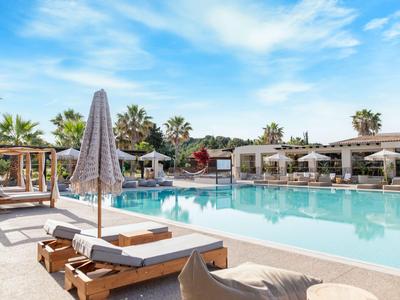Moderner Hotelpool mit Liegestühlen, Sonnenschirmen und Palmen unter blauem Himmel.