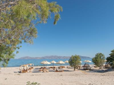 Strand mit Sand, Bänken, Sonnenschirmen und klarem blauem Himmel am Hotelstandort.