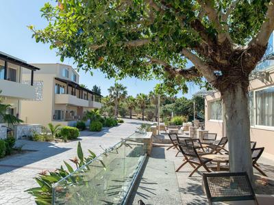 Moderner Hotelhof mit Außenterrasse, Stühlen und Bäumen in sonniger Atmosphäre.