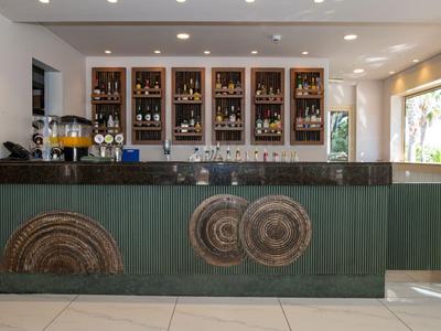 Moderner Hotelbarbereich mit grünem Tresen und dekorativen Holzscheiben an der Vorderseite.