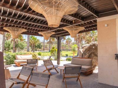 Überdachte Lounge mit modernen Sesseln und Sofas in einem Gartenhotel.