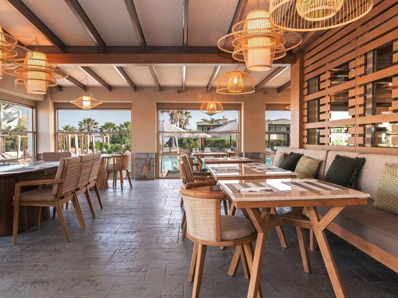 Moderní, útulná restaurace s dřevěným nábytkem a výhledem ven.