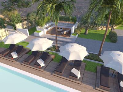 Bazénová oblast s lehátky, slunečníky a palmami v hotelové zahradě.