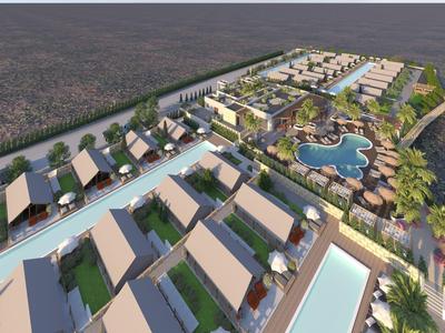 Letecký pohled na resort s vilami, bazény a velkým bazénovým komplexem obklopeným stromy.