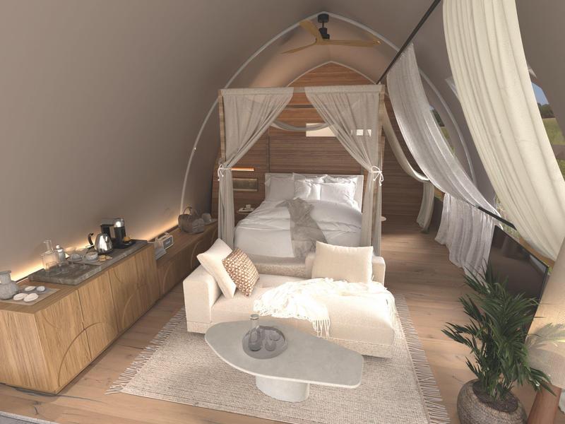 Pohodlný hotelový kout s bílou pohovkou, baldachýnovou postelí a dřevěným obložením v teplém osvětlení.