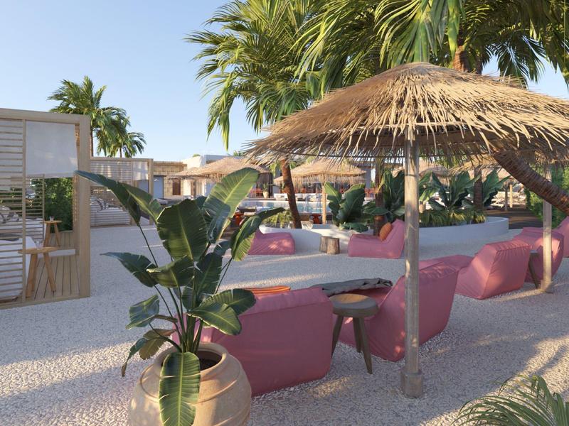 Venkovní prostor s růžovým posezením, slámovými slunečníky a tropickými rostlinami.