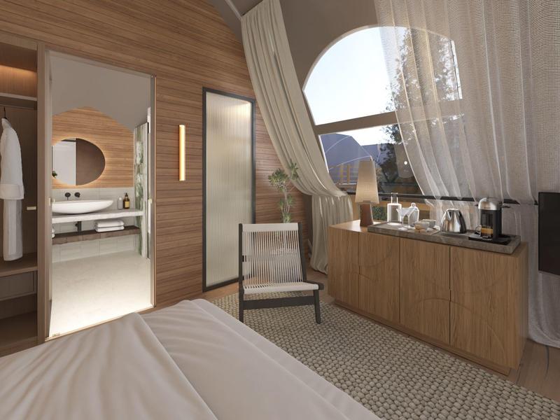 Moderní hotelový pokoj s dřevěnými stěnami, pohodlnou postelí, křeslem a velkým oknem s výhledem na hory.