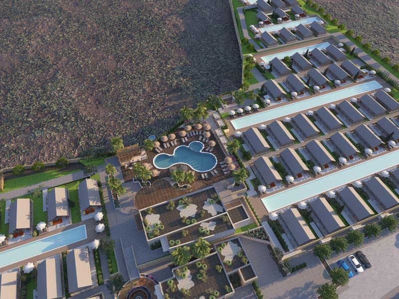 Letecký pohled na moderní resort s mnoha řadovými domy a centrálním bazénem