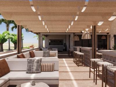 Zona de lounge exterior moderna con sofás cómodos, taburetes de bar y vista a palmeras.