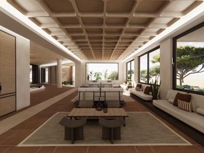 Salón moderno de hotel con sofás, mesas de madera y grandes ventanales con vistas a la naturaleza.