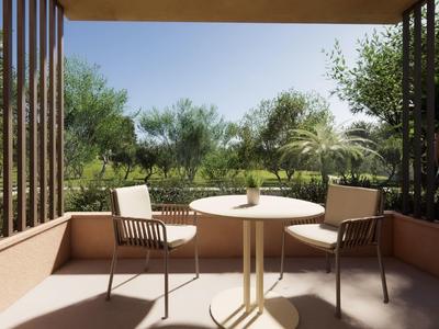 Balcón con mesa y dos sillas con vista a árboles verdes y cielo azul.