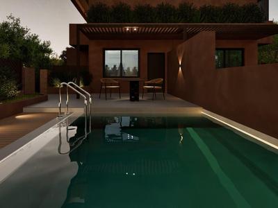 Área de piscina exterior moderna al anochecer con asientos y cerca plantada.