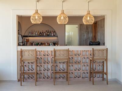 Modern hotel bar area with wooden stools and stylish pendant lights in warm lighting.