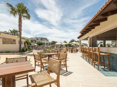 Modern outdoor area with tables, chairs, and bar in a sunny vacation spot.