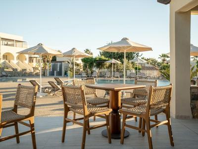 Pool area with wooden chairs, tables, and umbrellas at a modern hotel.