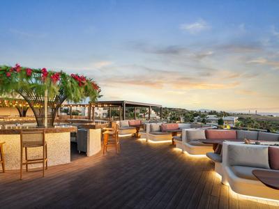 Rooftop terrace with cozy seating and decorations at sunset in a hotel.