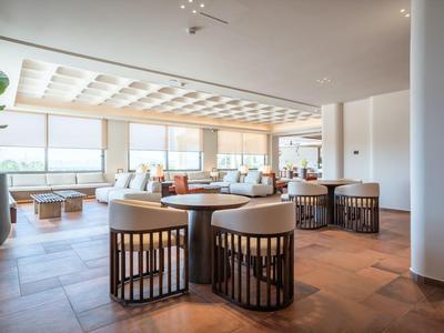 Modern, bright hotel lounge area with large windows and comfortable seating.