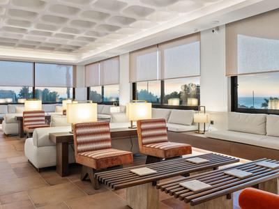 Modern hotel lounge area with large windows and comfortable seating.