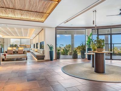 Bright hotel interior with large windows, plants, and modern design.