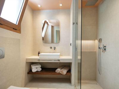Small bathroom with shower, washbasin, mirror cabinet, and window for natural light.