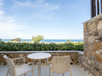 Terrace with a seating area featuring white plastic chairs and a round table overlooking the sea.