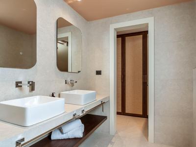 Modern hotel bathroom with two sinks, large mirrors, and beige decor.