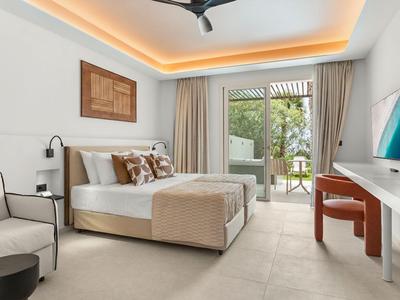 Modern hotel room with double bed and terrace access overlooking garden.