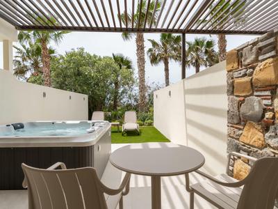 Private outdoor area with hot tub, seating, and shade structure, ideal for hotel relaxation.