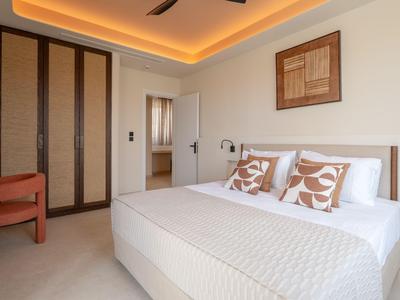 Modern hotel room with large bed, two pillows, comfortable chair, and decorative wall art.