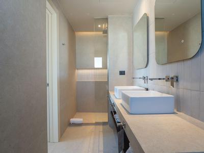 Modern bathroom with two white sinks, large mirrors, and clean design.