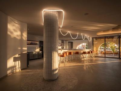 Area lounge moderna dell'hotel con bar, posti a sedere e luce calda serale.