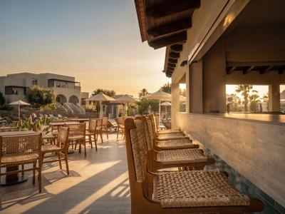 Terrazza dell'hotel soleggiata con sedie e tavoli in legno al tramonto.