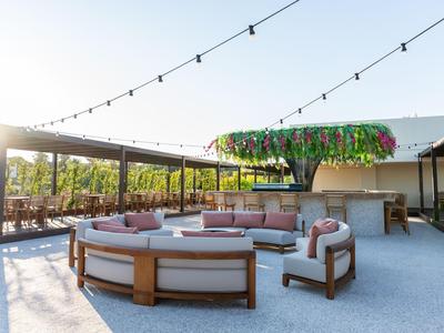 Moderna terrazza esterna con comodi posti a sedere e tenda parasole al tramonto.