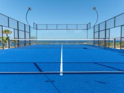 Campo da paddle tennis blu con rete e vista chiara su cielo azzurro e mare.