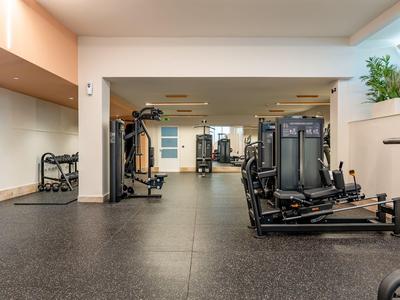 Palestra moderna in hotel con attrezzature e colori neutri.