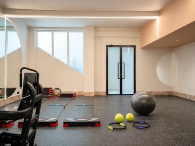 Palestra moderna dell'hotel con tappetini, palloni e specchi.