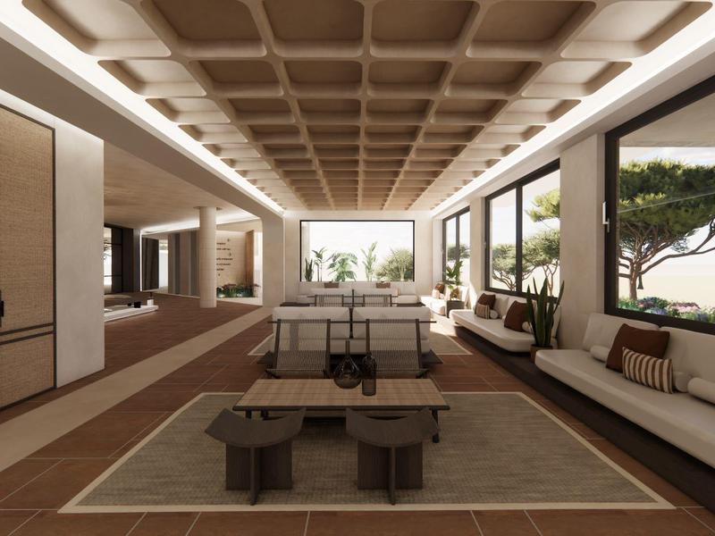 Salón moderno de hotel con sofás, mesas de madera y grandes ventanales con vistas a la naturaleza.