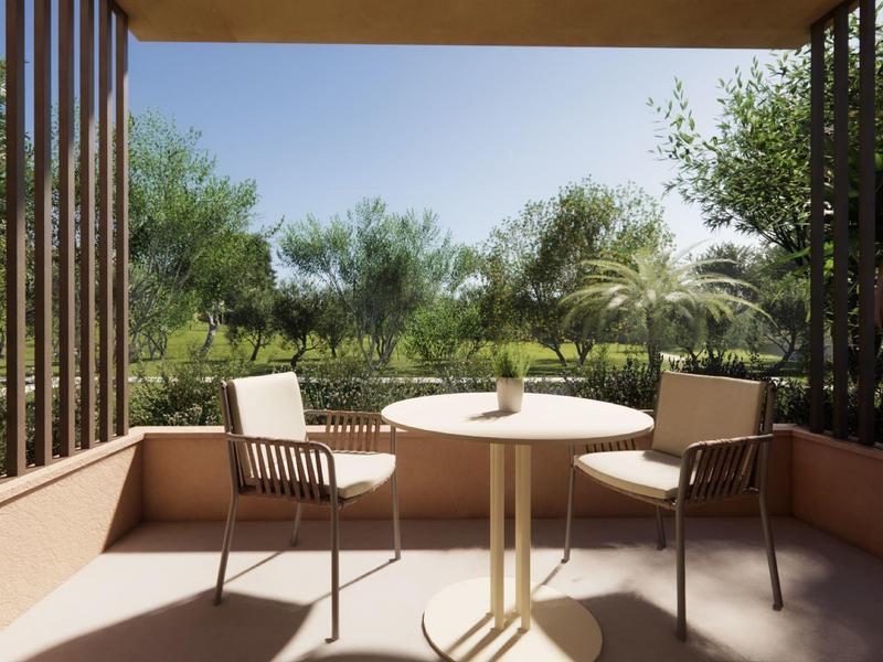 Balcón con mesa y dos sillas con vista a árboles verdes y cielo azul.